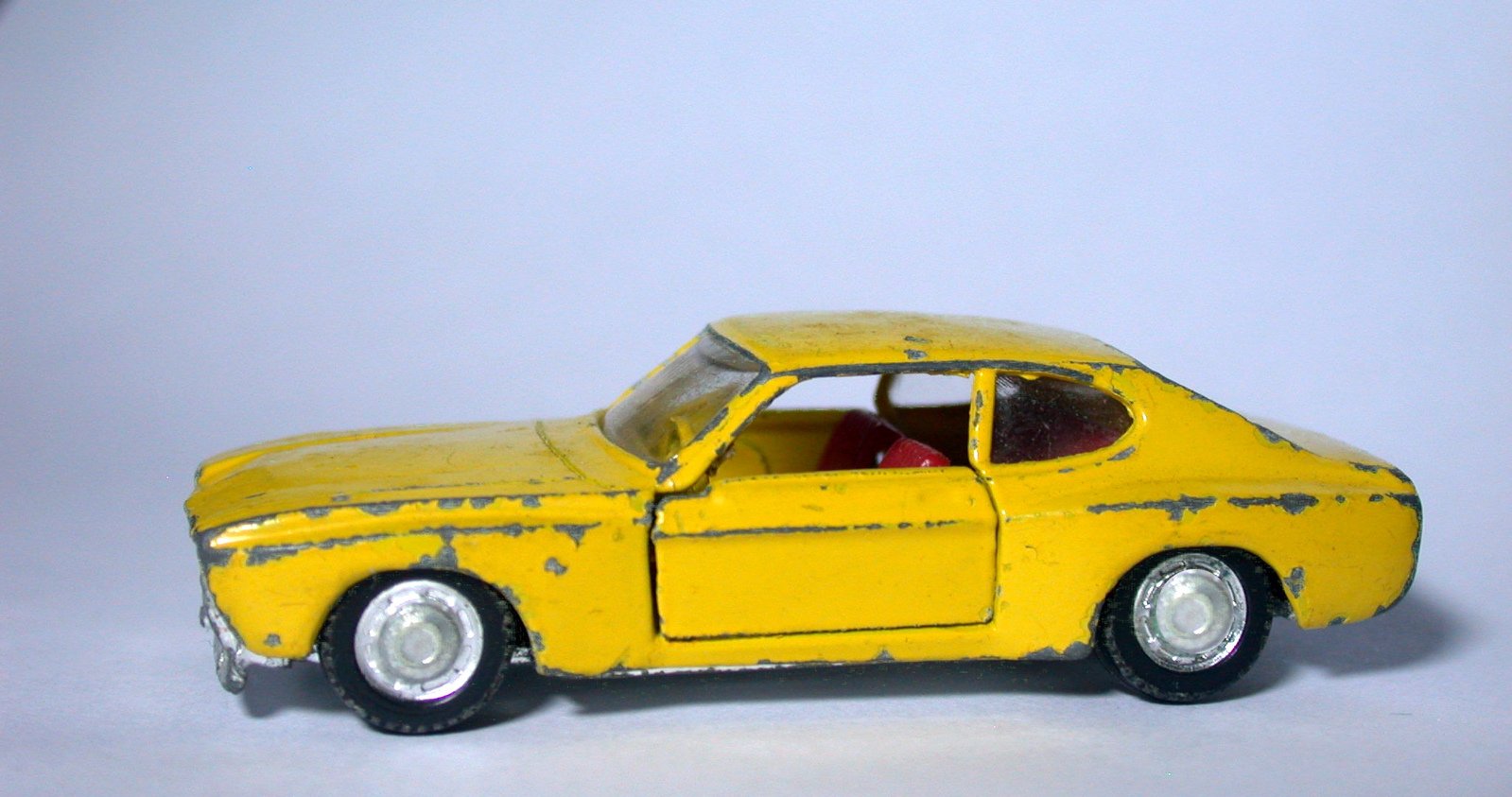 an old yellow toy car sitting on a table