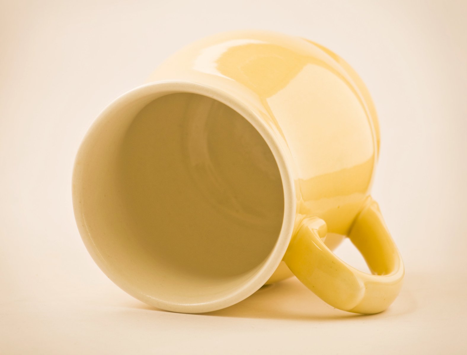 a yellow mug with its handles partially pulled up against the wall