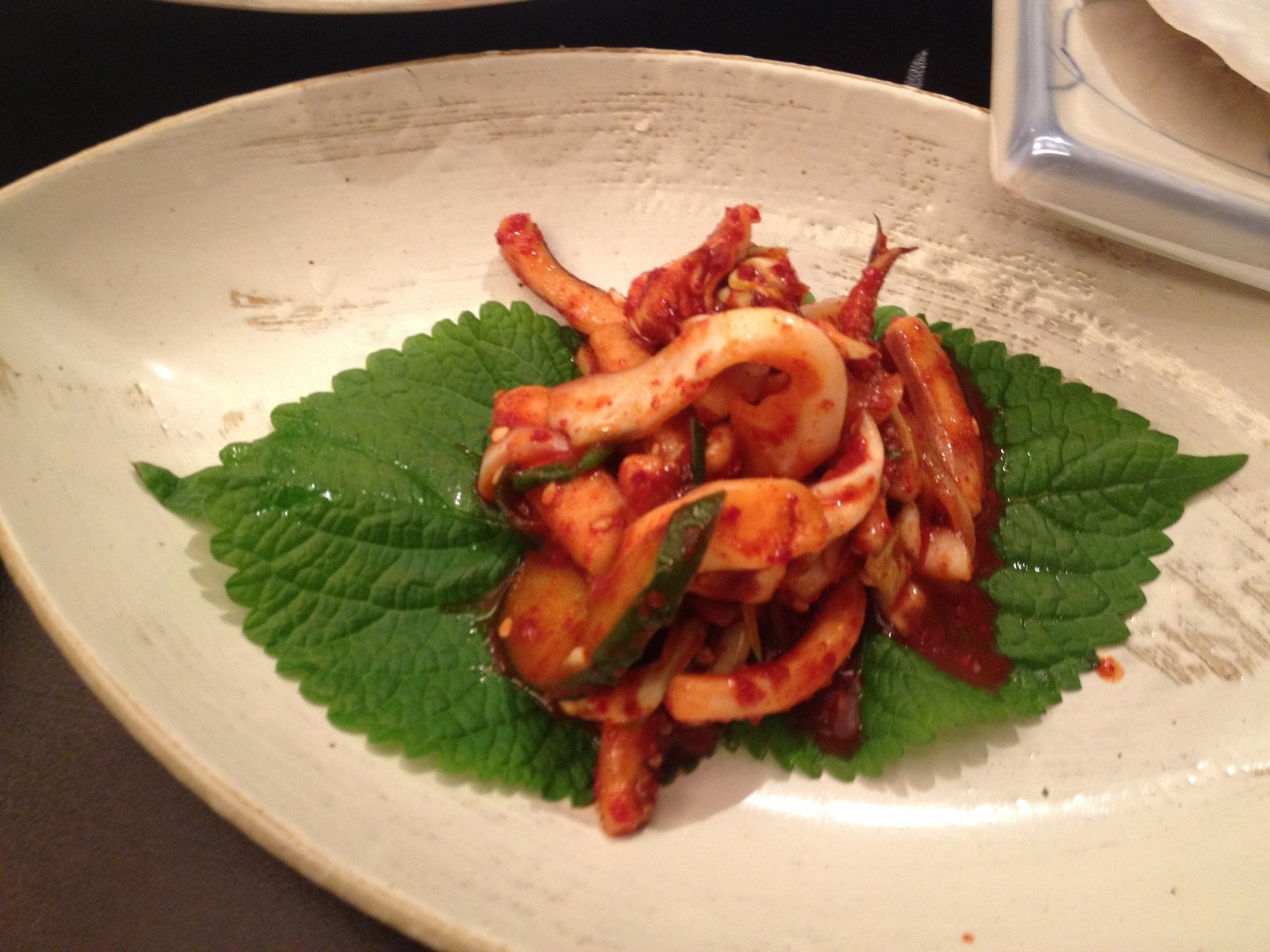 a white plate topped with shrimp on top of green leafy vegetables