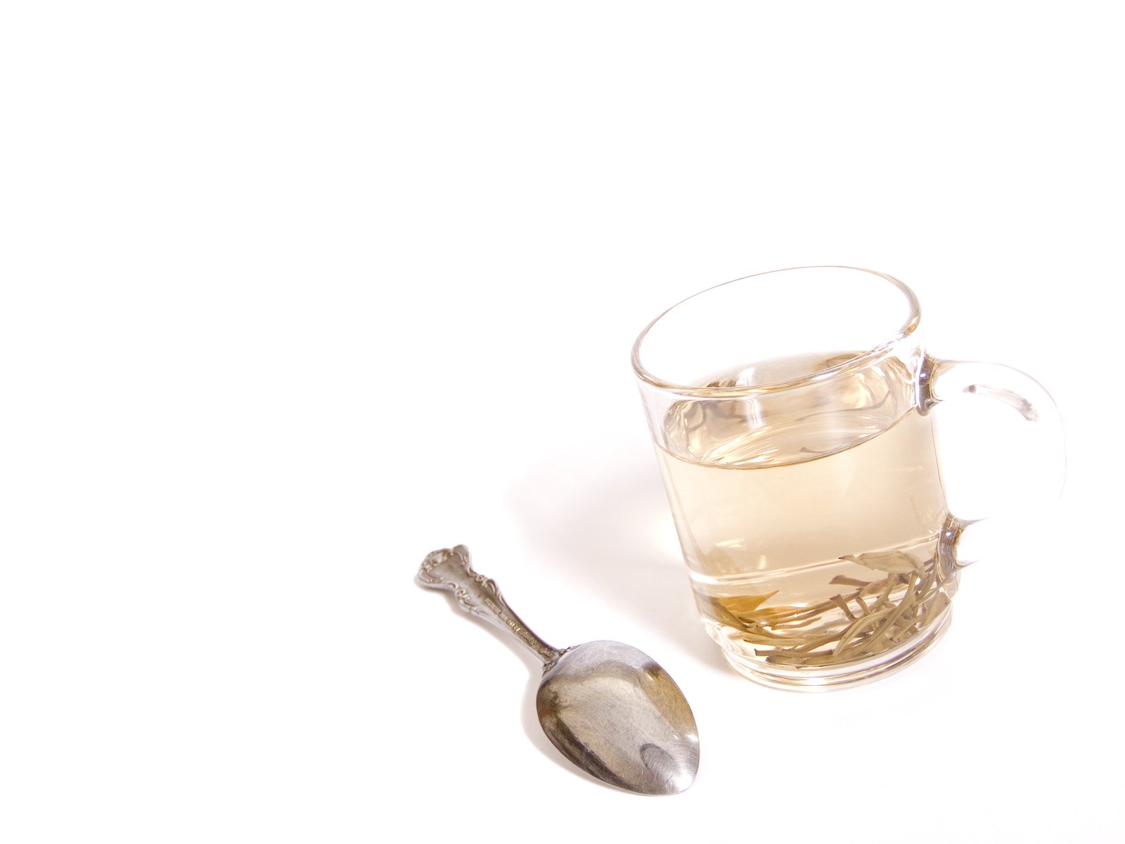 a glass mug of tea with a spoon and a silver spoon