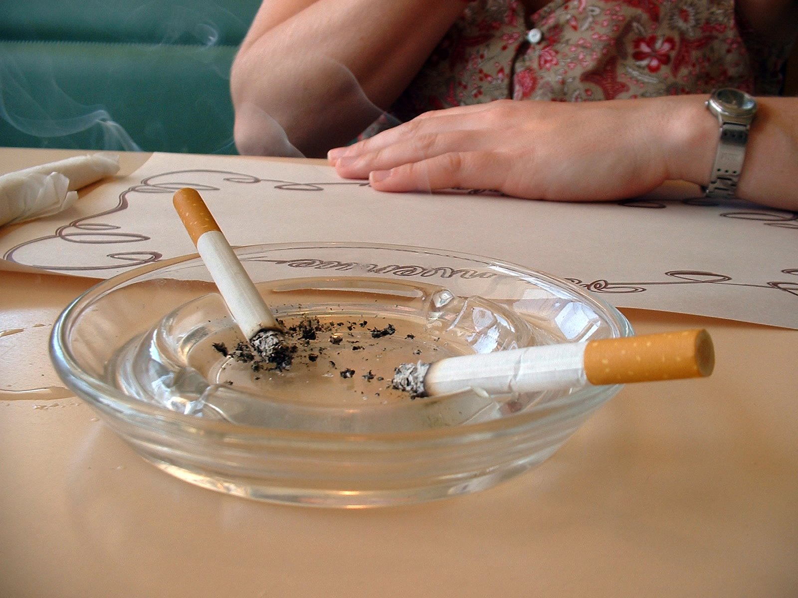 a woman smoking cigarettes and a glass bowl of ashtrays