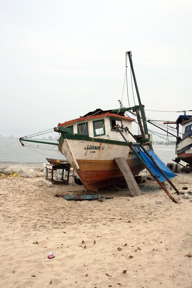 a white and green boat is on the sand