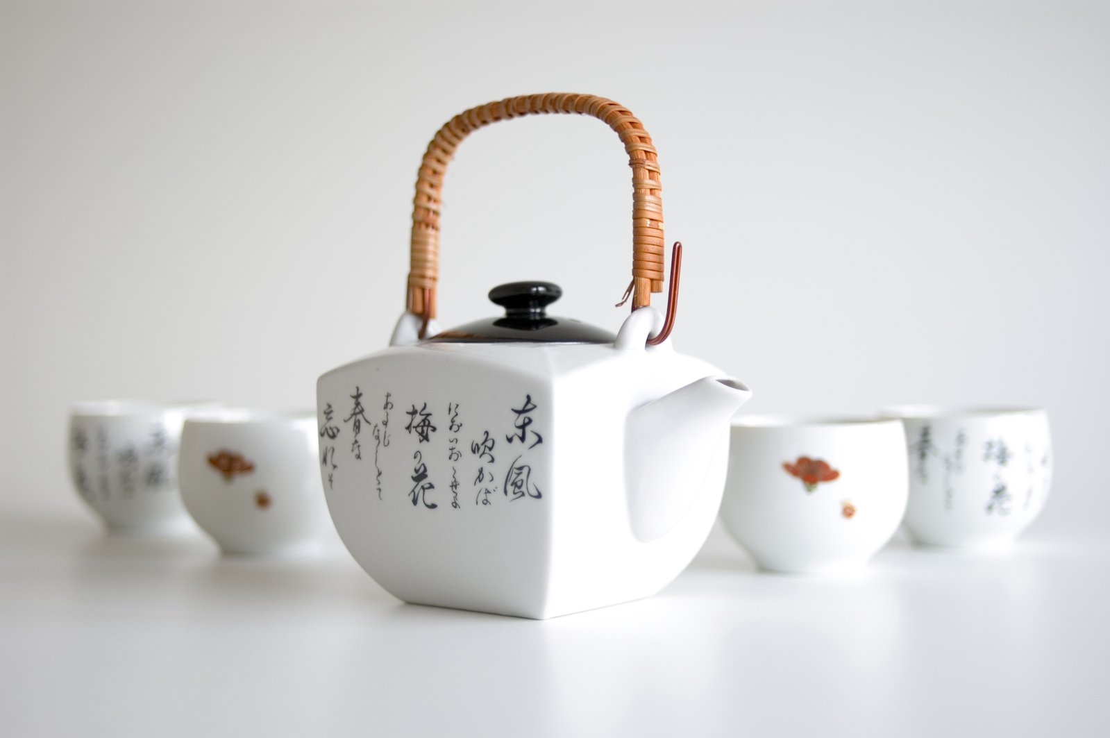 several tea cups and a kettle sitting in the middle of the white table