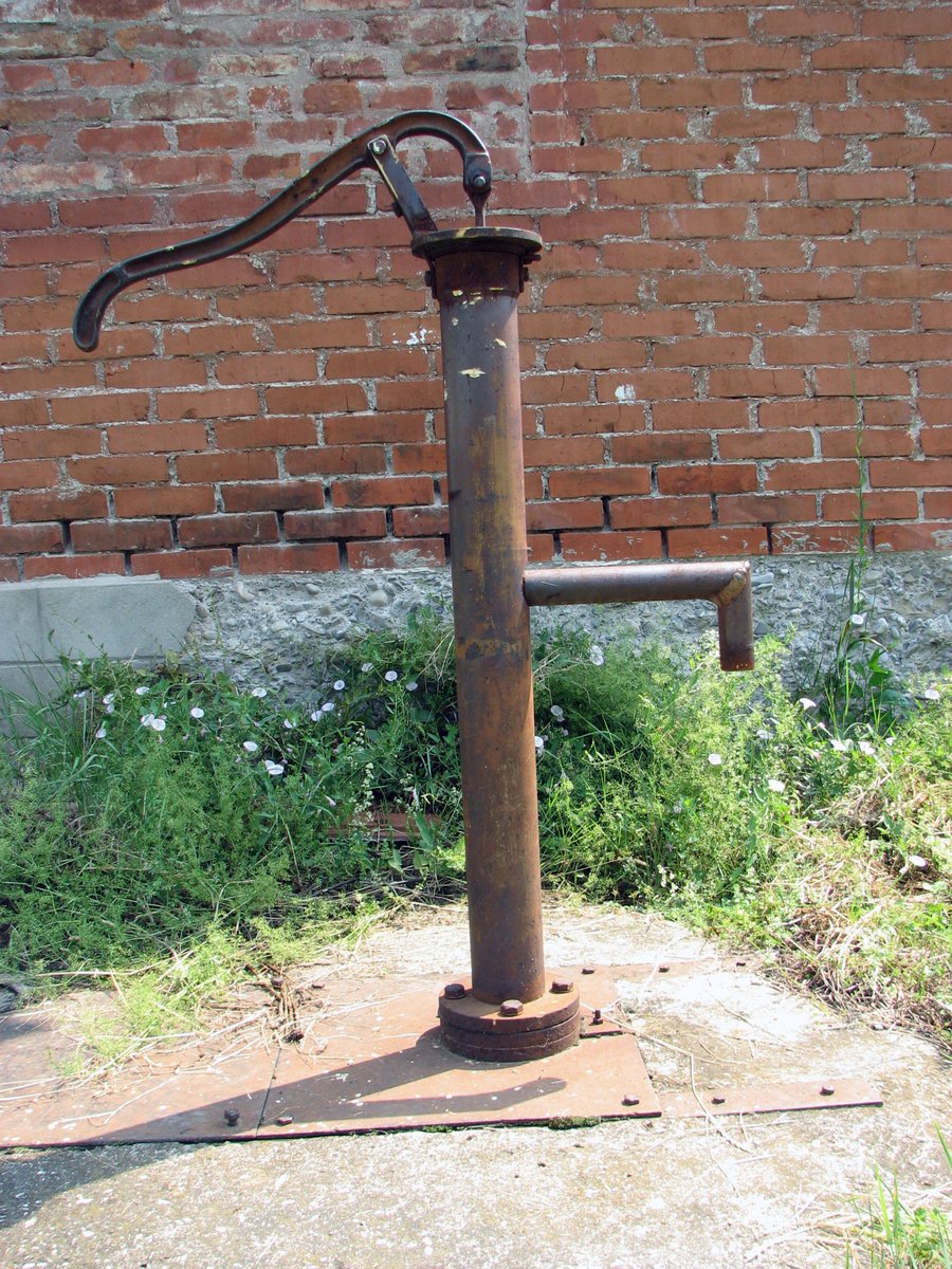 a water main pole and faucet next to a brick wall