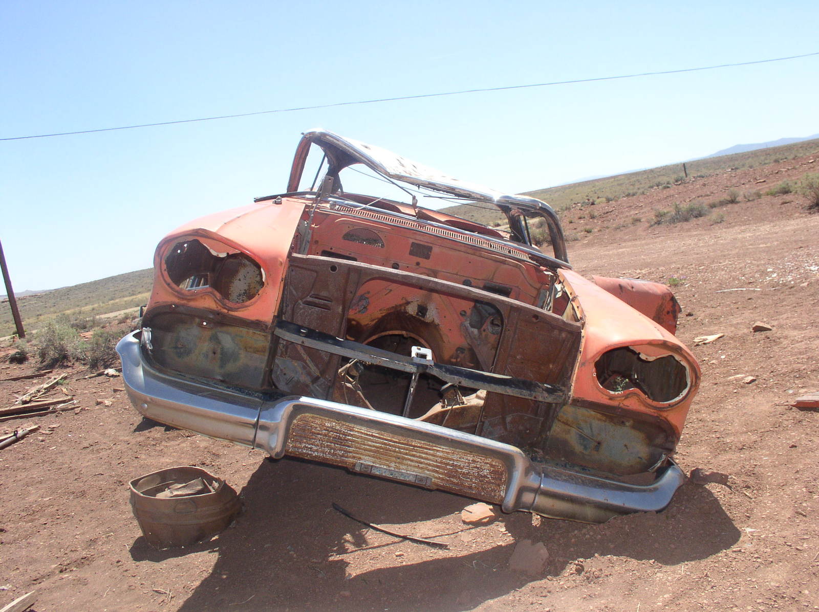 a rusty, burnt car sitting in a barren area