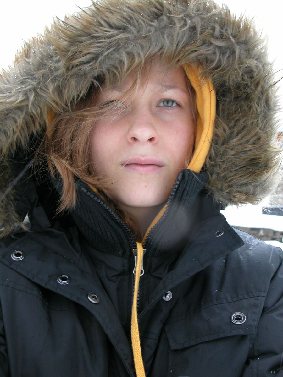 young child in black coat looking to camera with white background