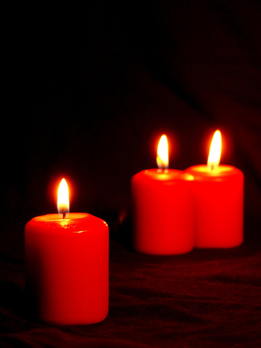 three red candles lit up with one glowing red