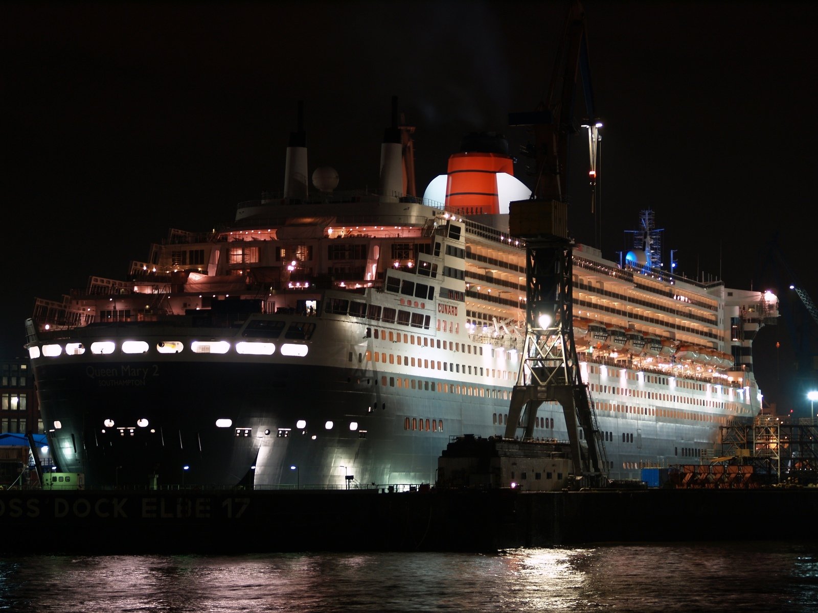 a large ship docked at night with its lights on