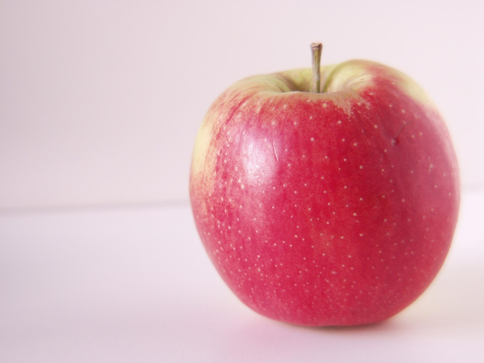 an apple with several speckles is against a white background