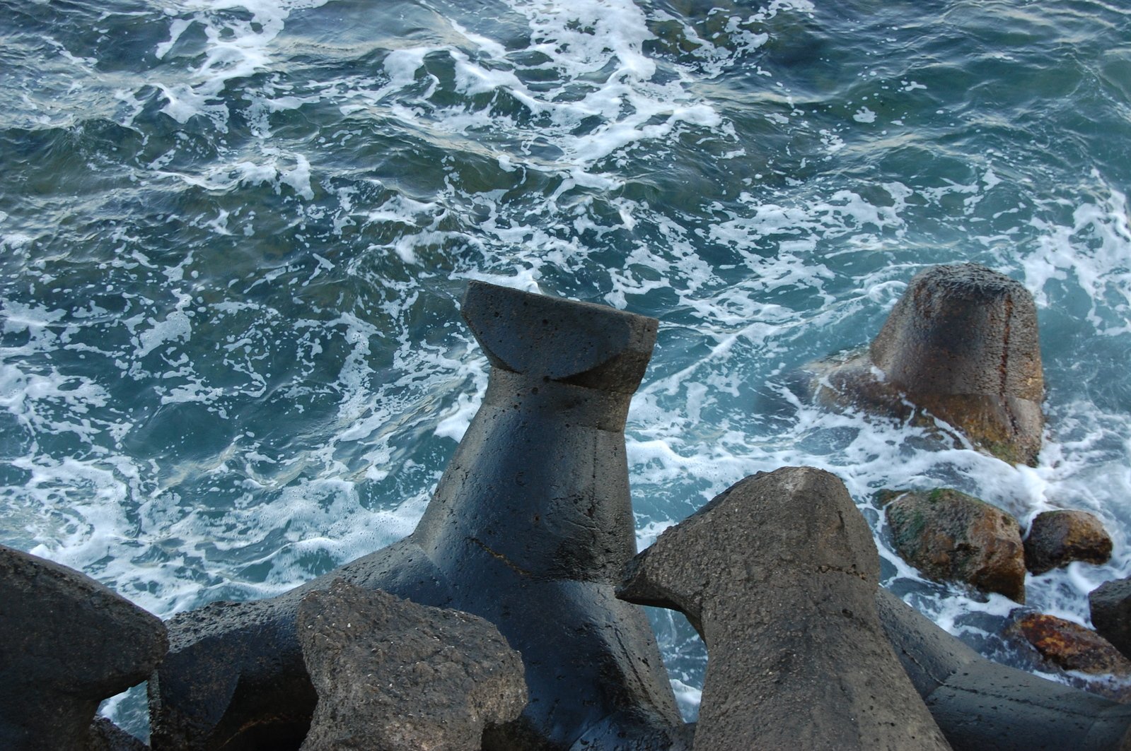 a rock and water next to the beach