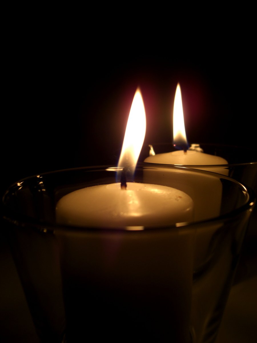 three white candles sit in a glass cup