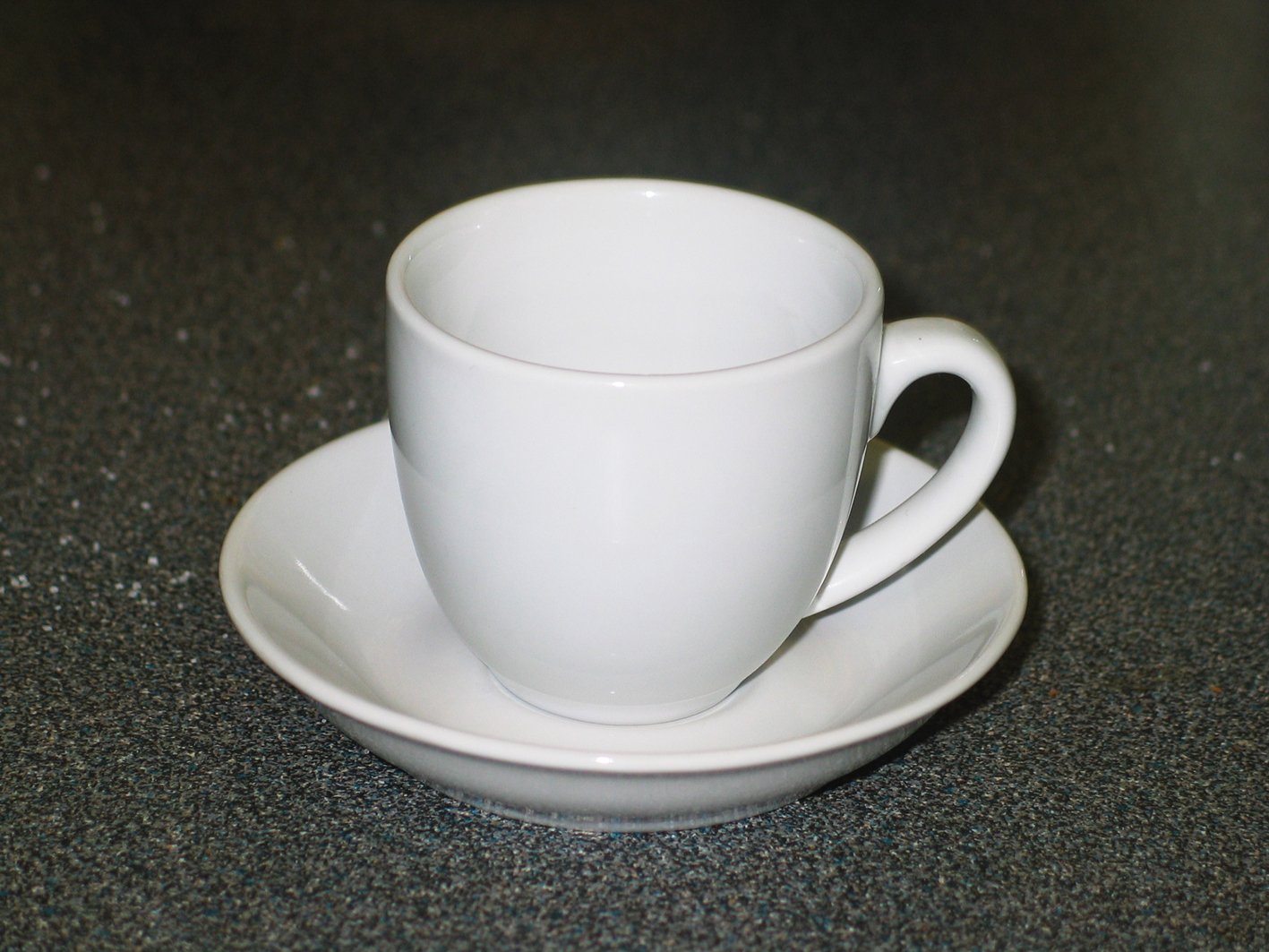 a white cup and saucer set on a table