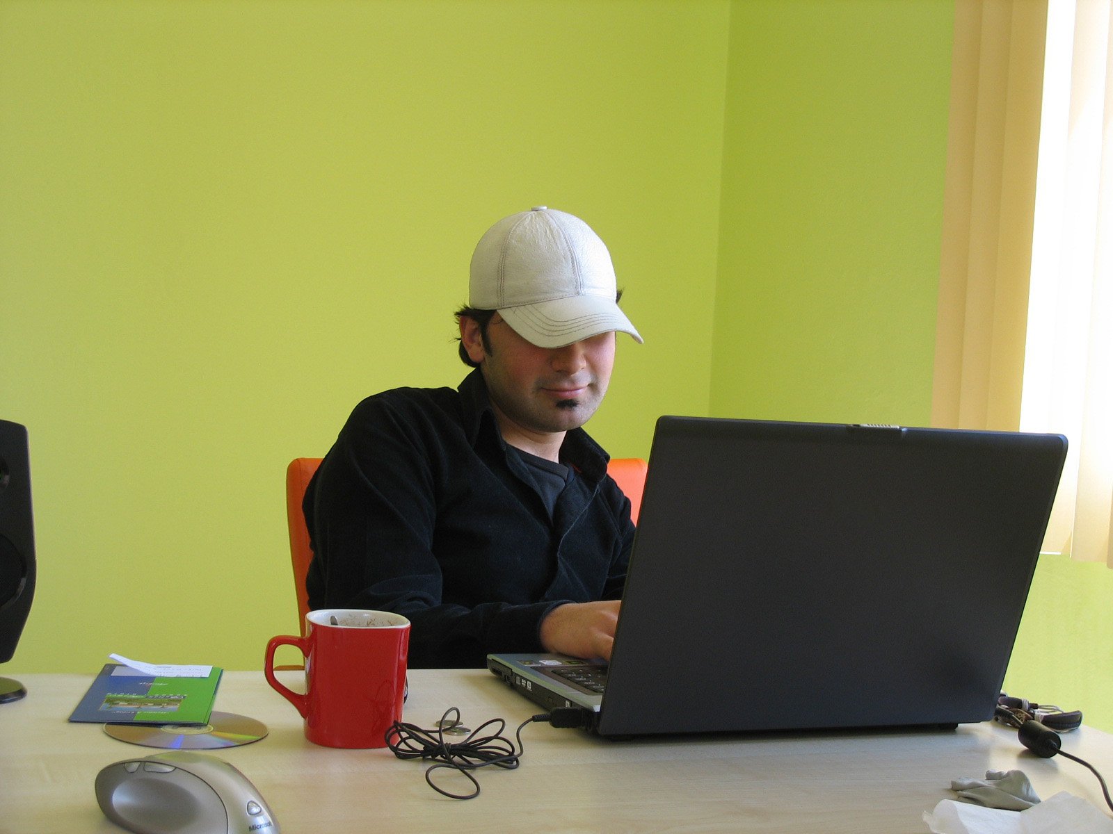 a man sits at a table while using his laptop