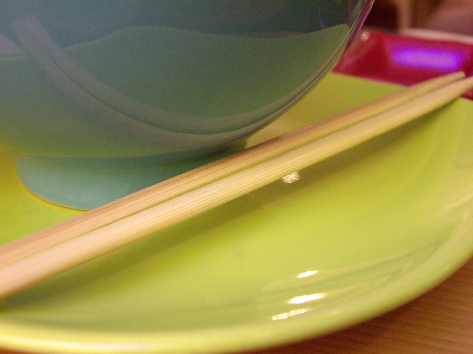 a yellow plate topped with two chopsticks and a bowl