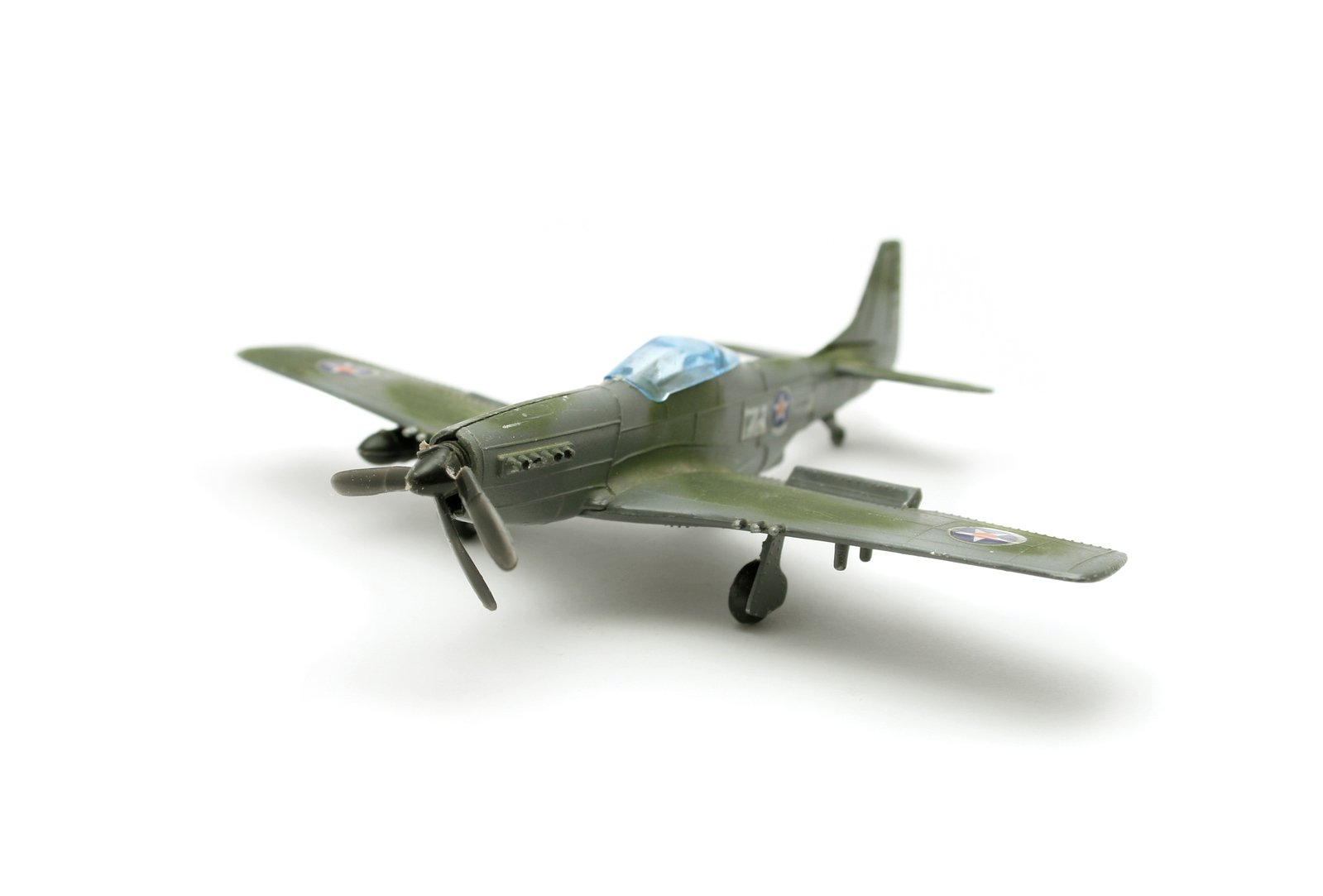 a green toy model airplane on a white surface