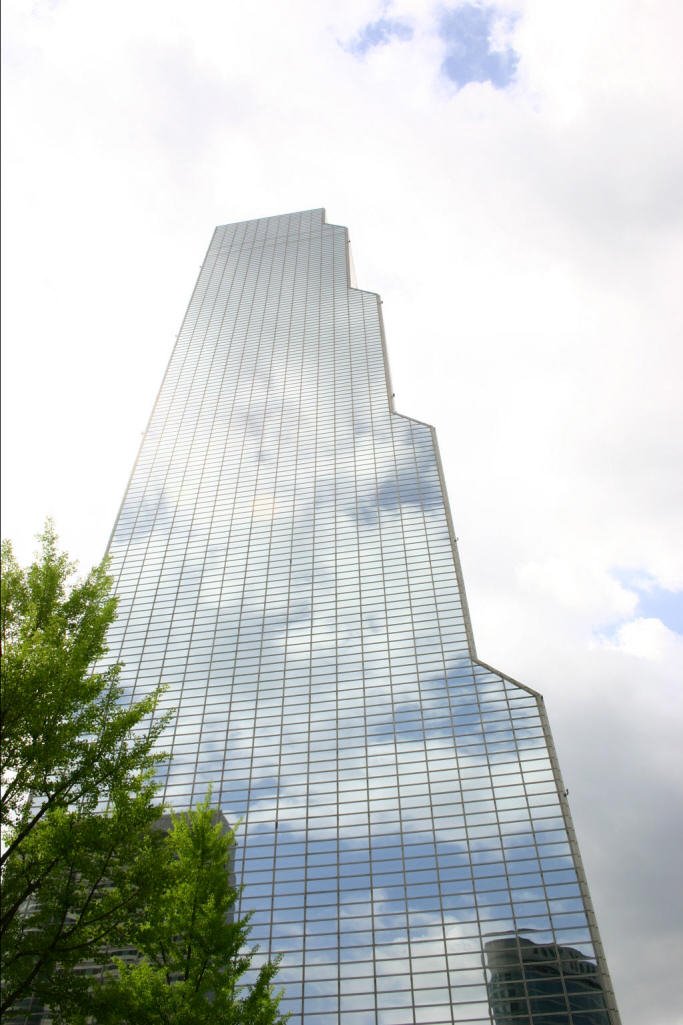 some clouds are reflected in the glass windows of the building