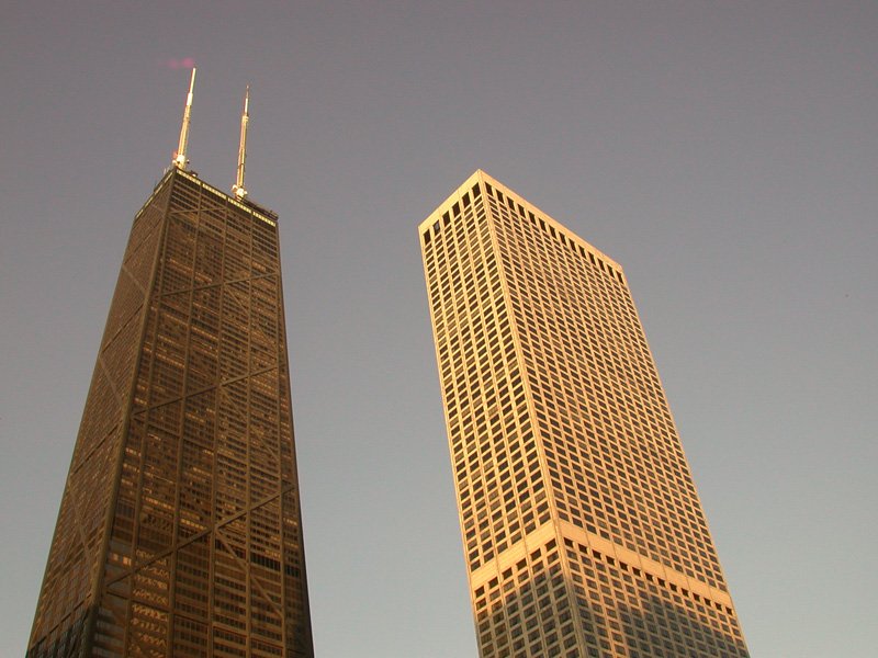 a pair of very tall buildings under the blue sky
