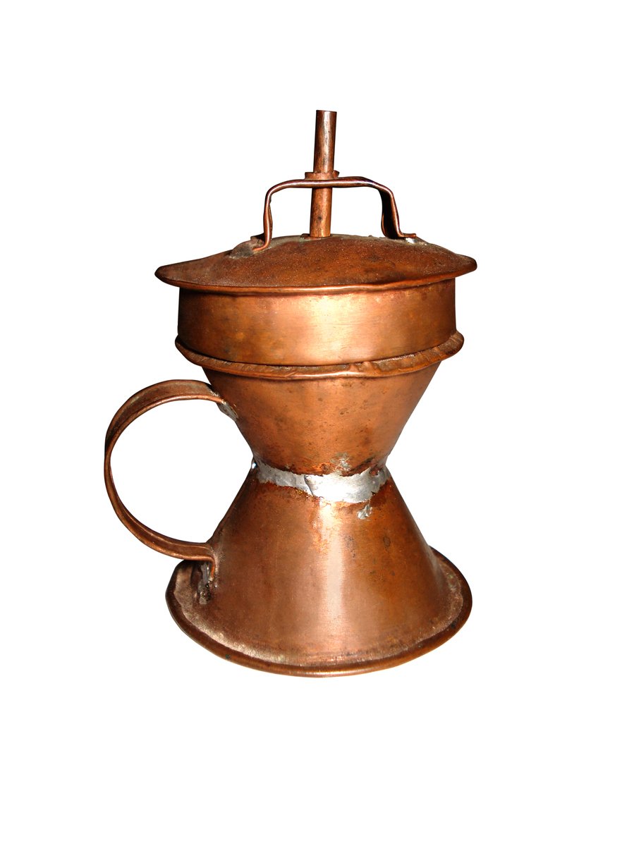 a copper colored coffee pot sitting on top of a table