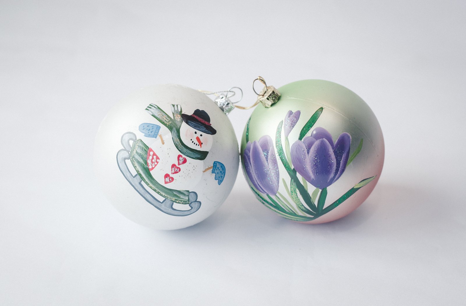 two christmas baubles with designs of flowers on them