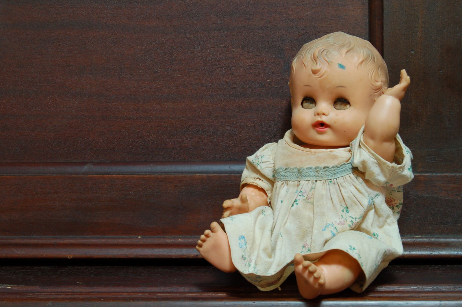 a close up of an infant doll on a wood table