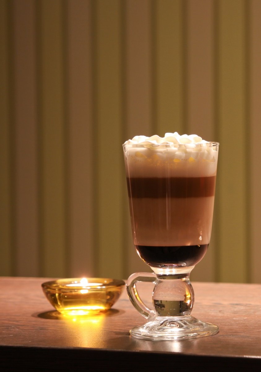 a glass cup of coffee is next to a small yellow bowl