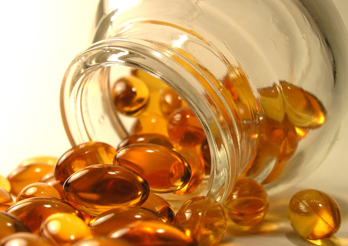 a glass jar filled with yellow gumballs next to a white background