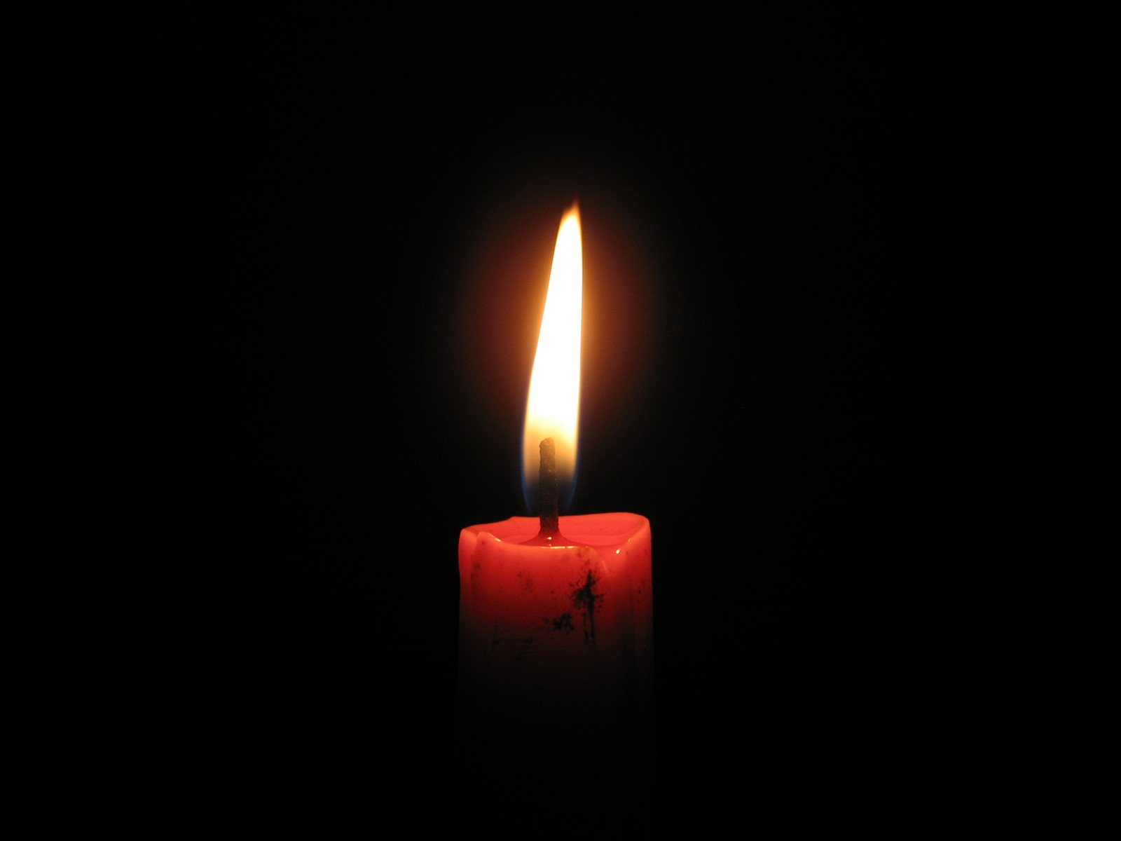 a lit candle is on a black background