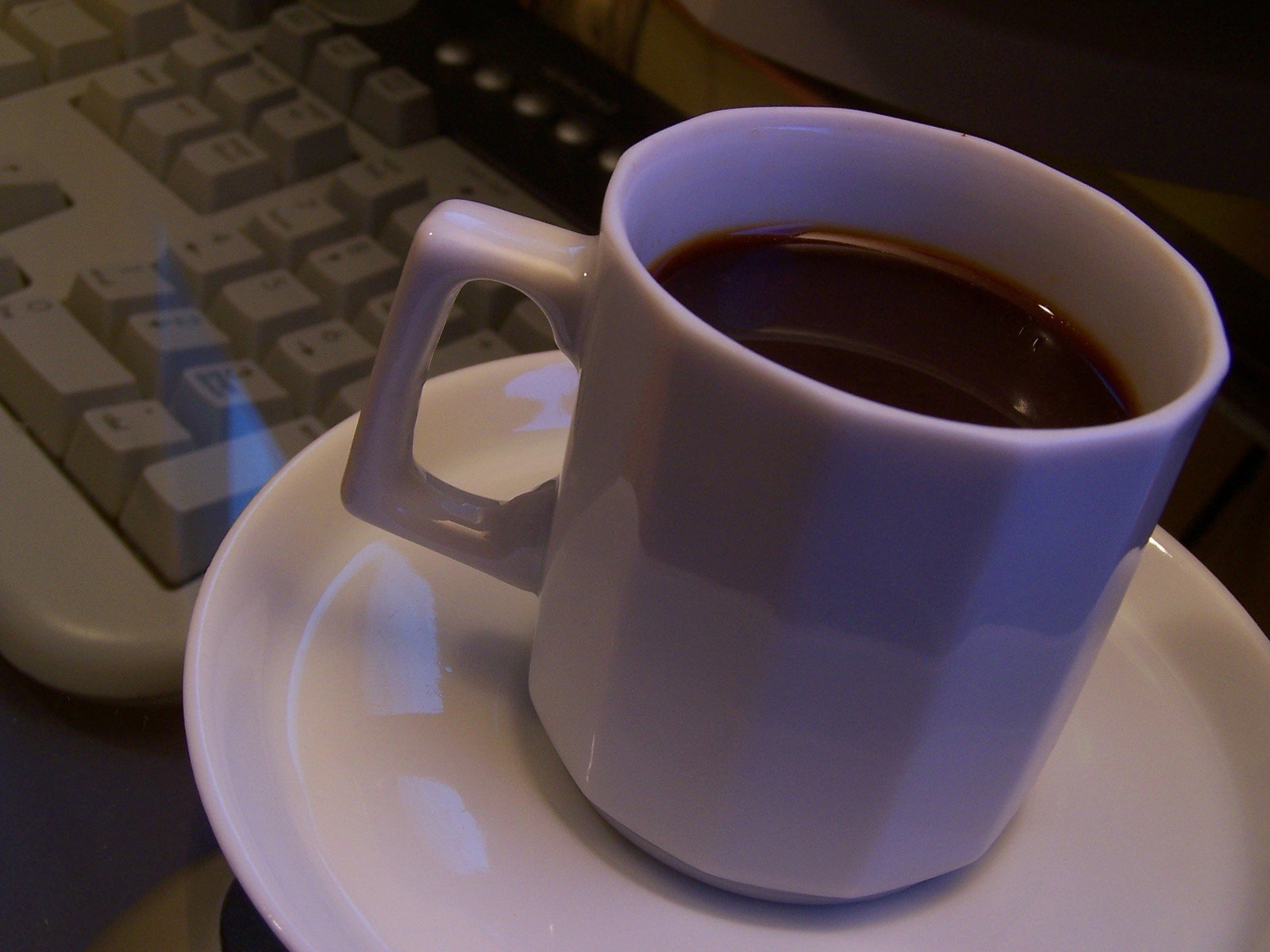 a cup of coffee with dark saucer on the side