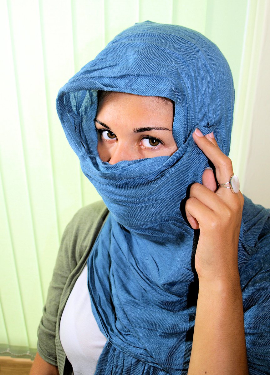a woman in a blue scarf holding her head