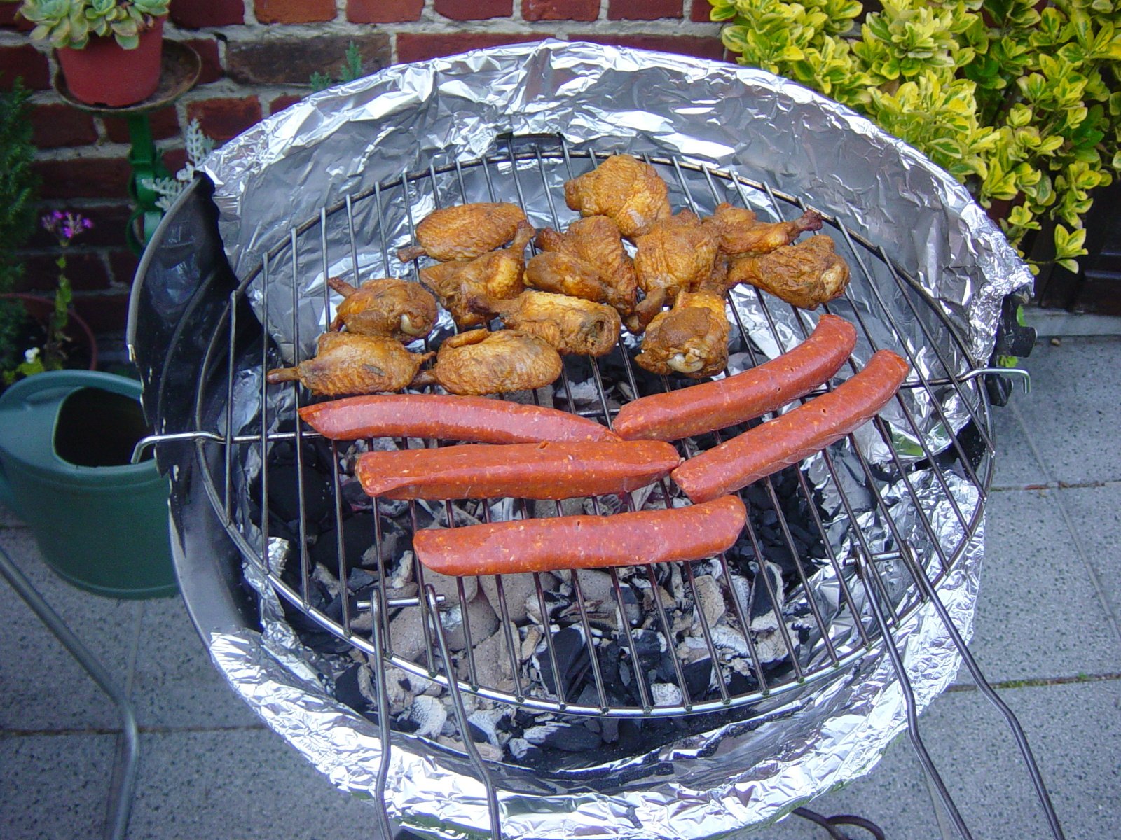 grilled  dogs, rolls, and onions cooking on an outdoor charcoal grill