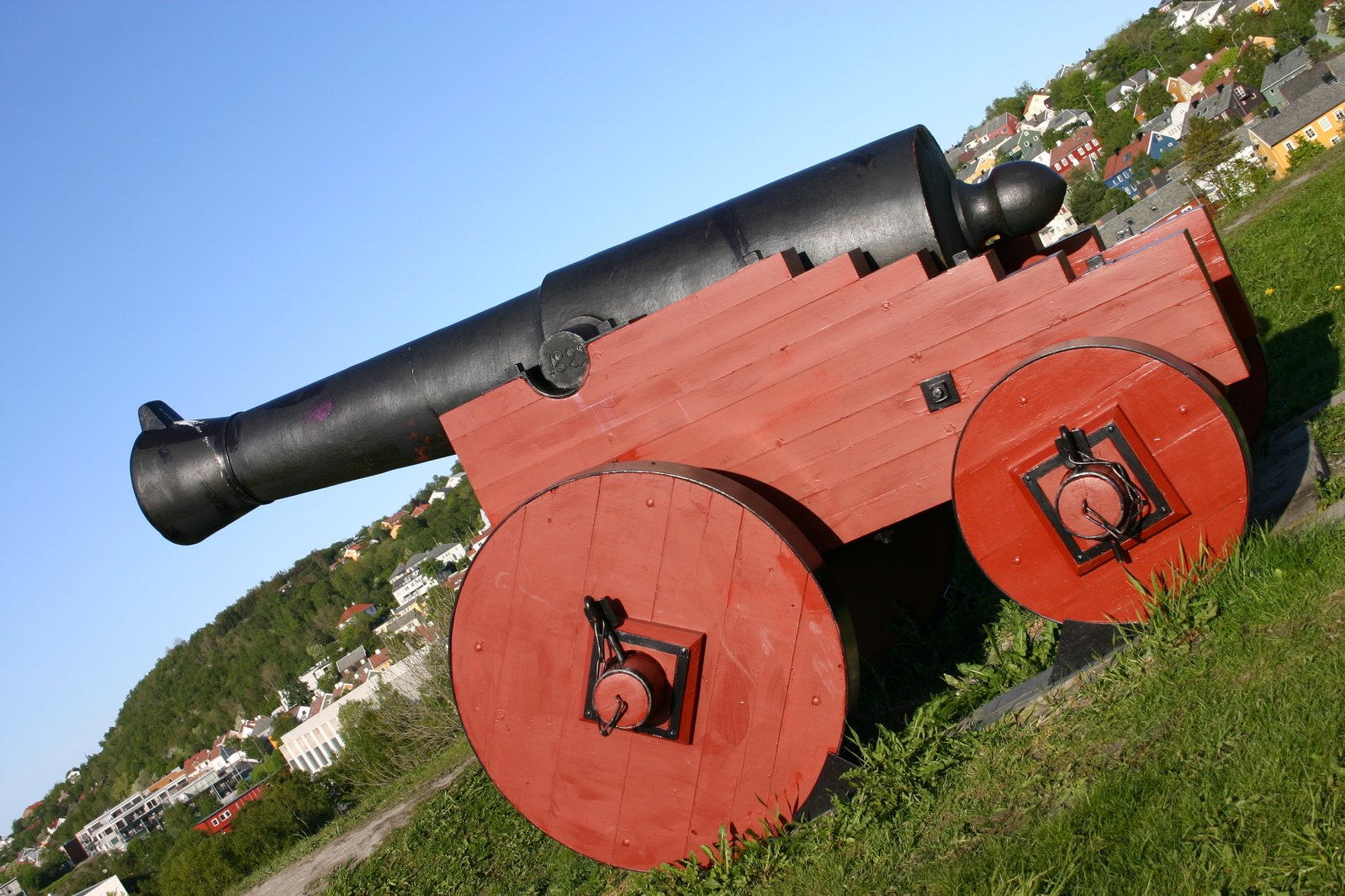 a large red wooden cannon like object sits in a field of green grass