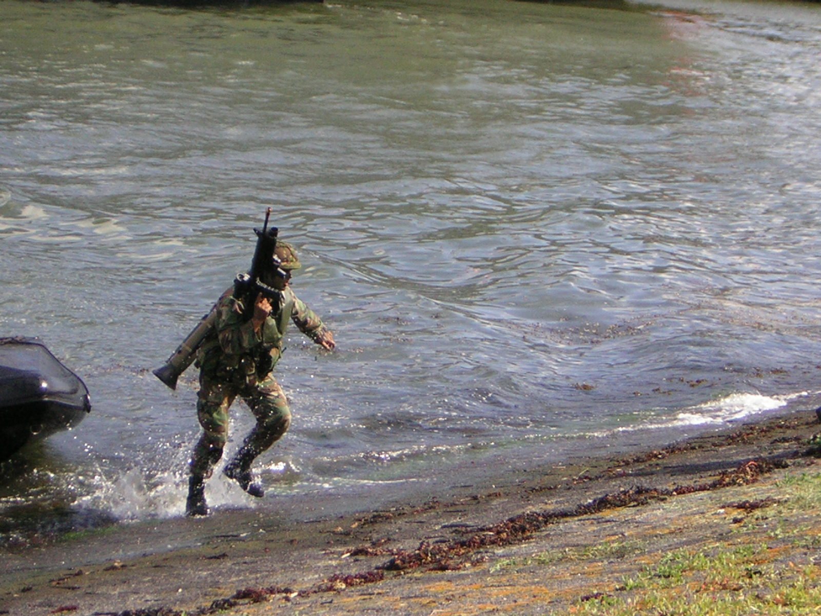 a soldier splashing through the water with a rifle