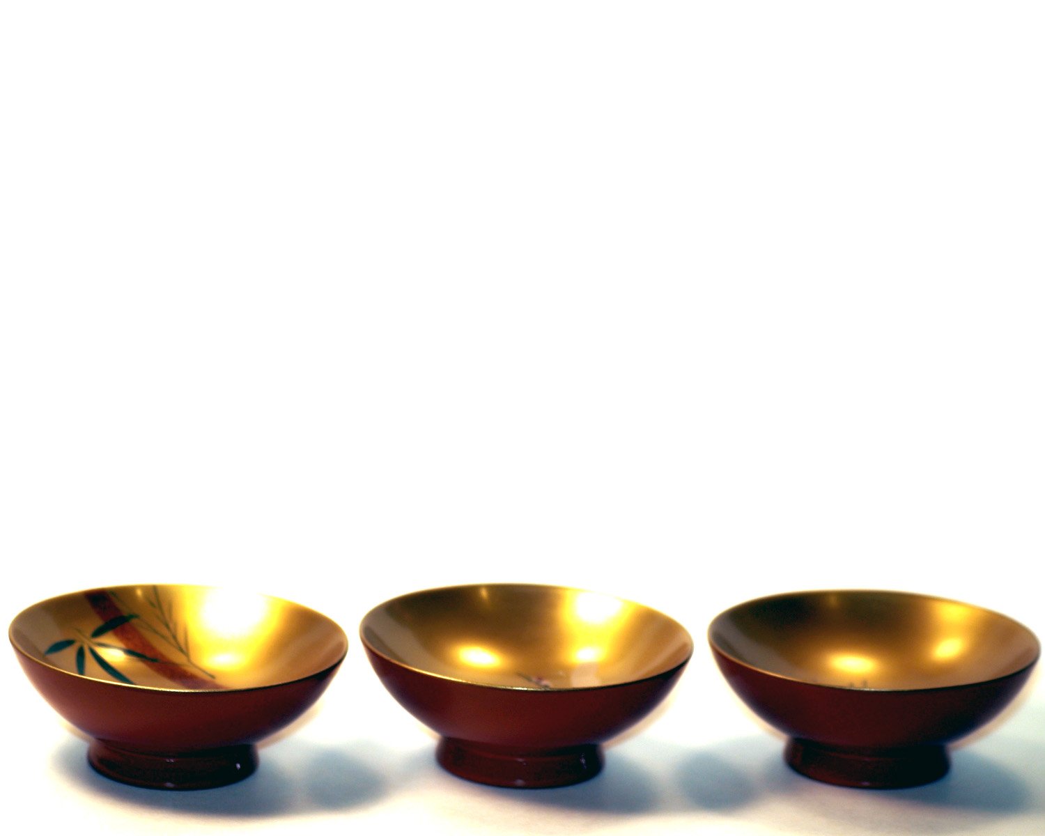 three golden bowls sitting on top of a table