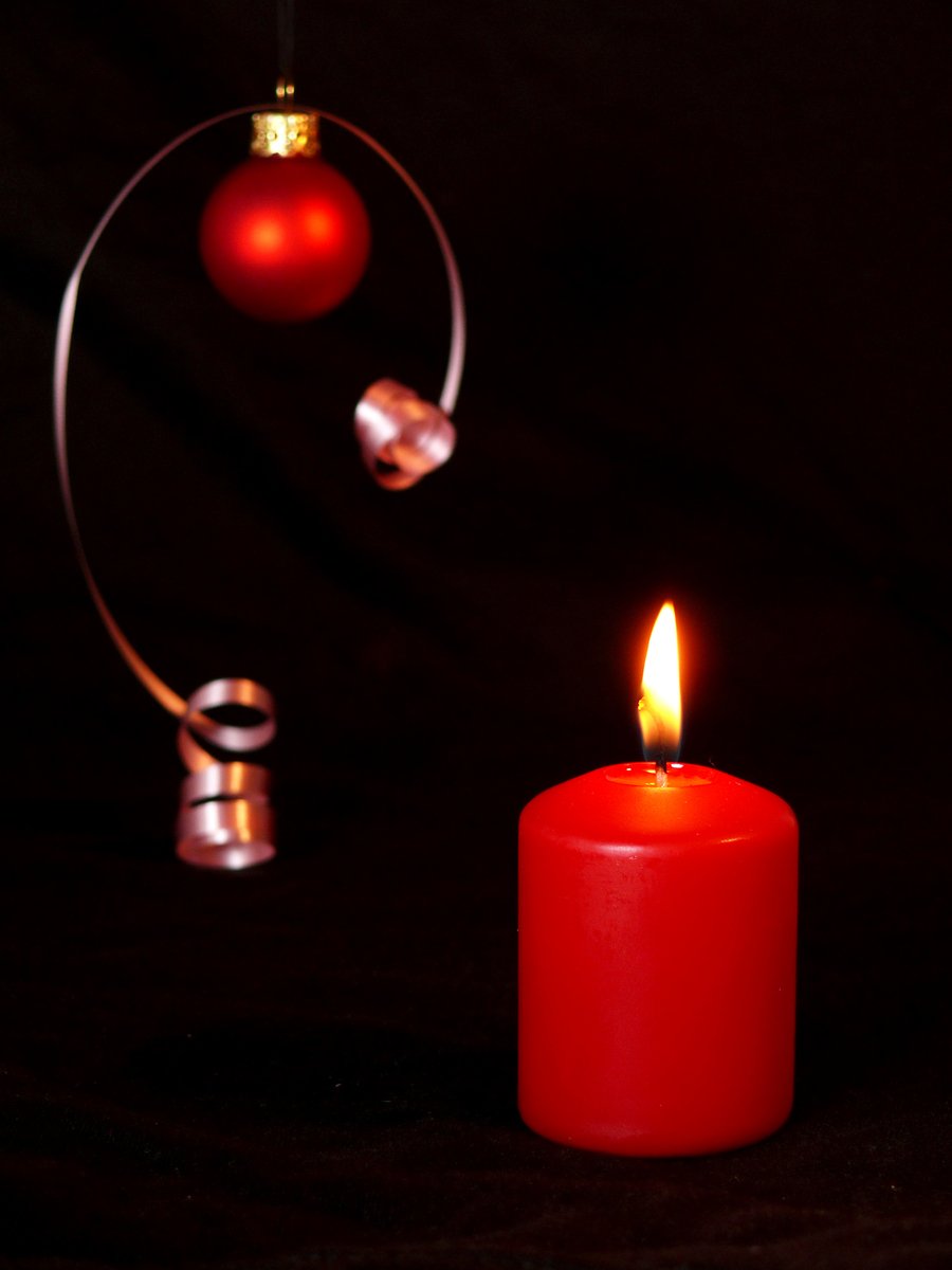 a red candle with a silver circle and ornament hanging from the end