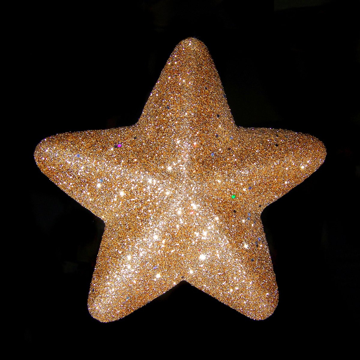 a gold star ornament hanging on a dark background