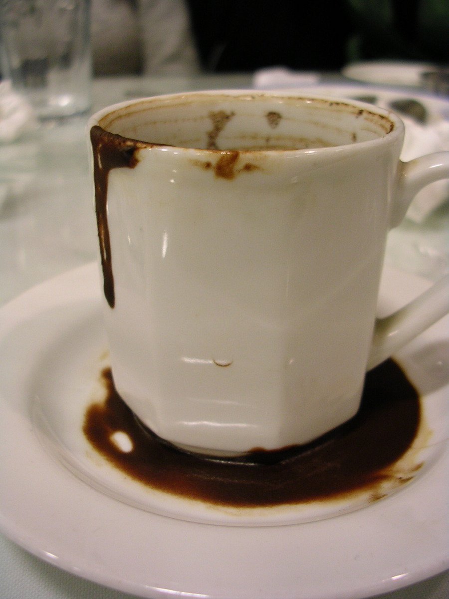 a cup on a plate with sauce, with chocolate being poured