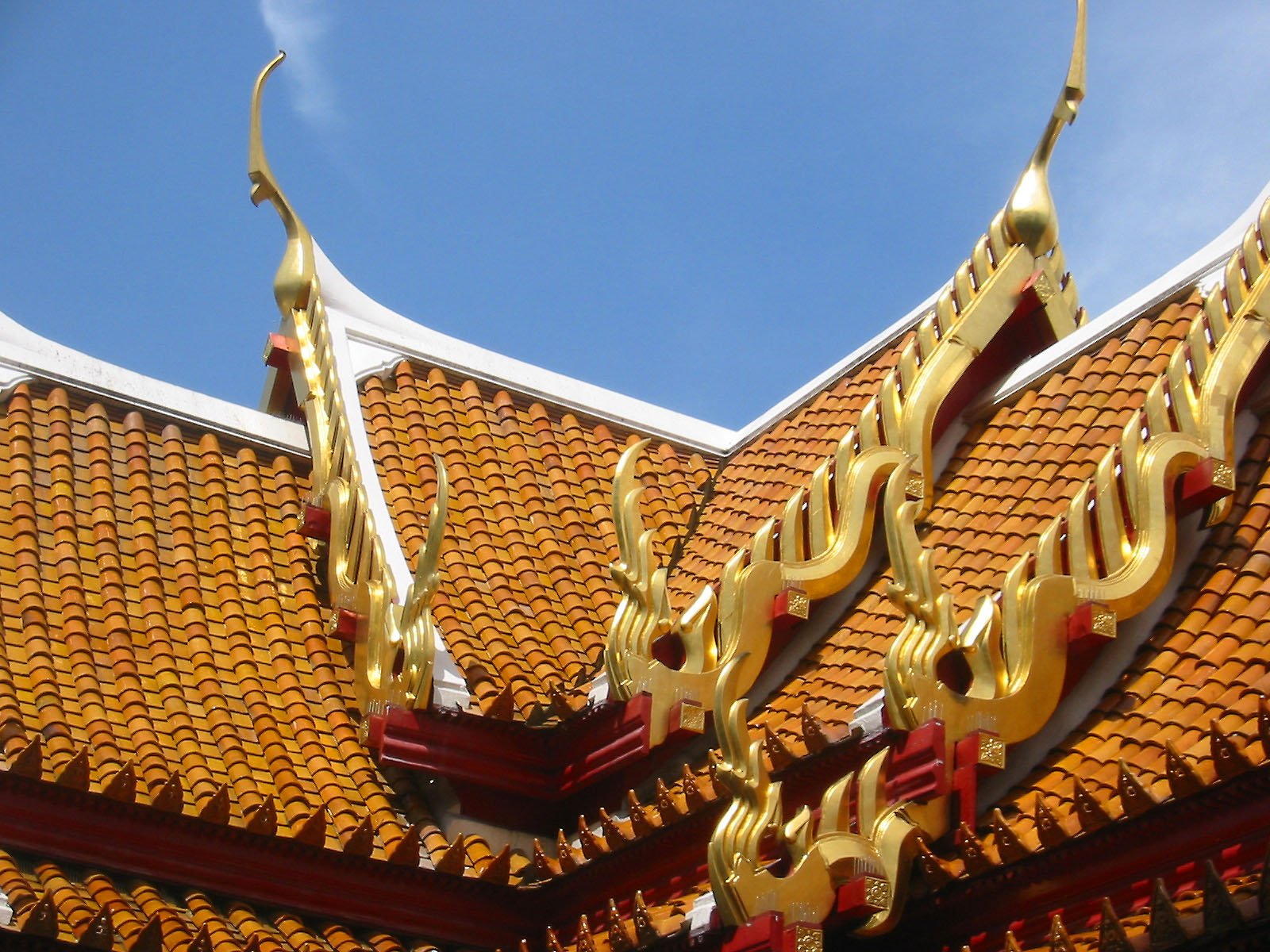 the golden roof decoration on the building has a blue sky in background