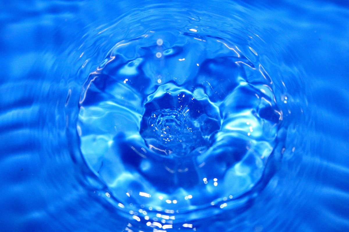 a blue liquid drop falling into the water