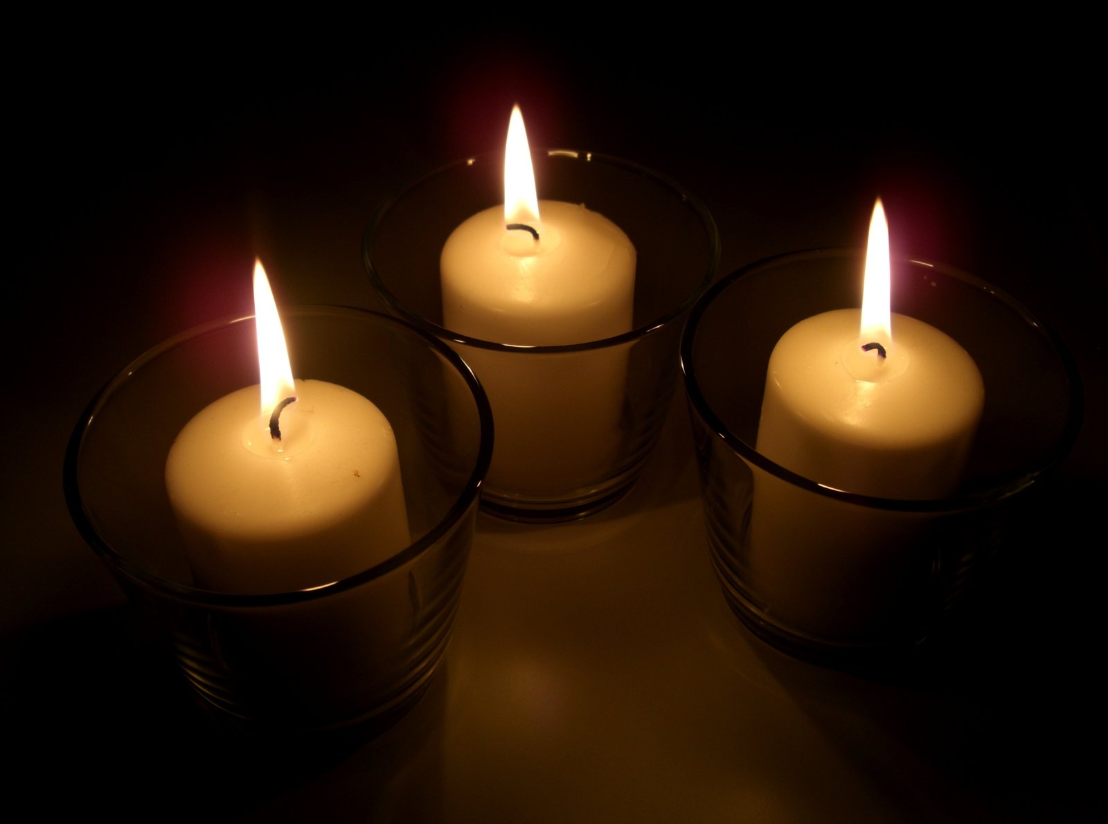 four candles are lit in the dark and are glowing