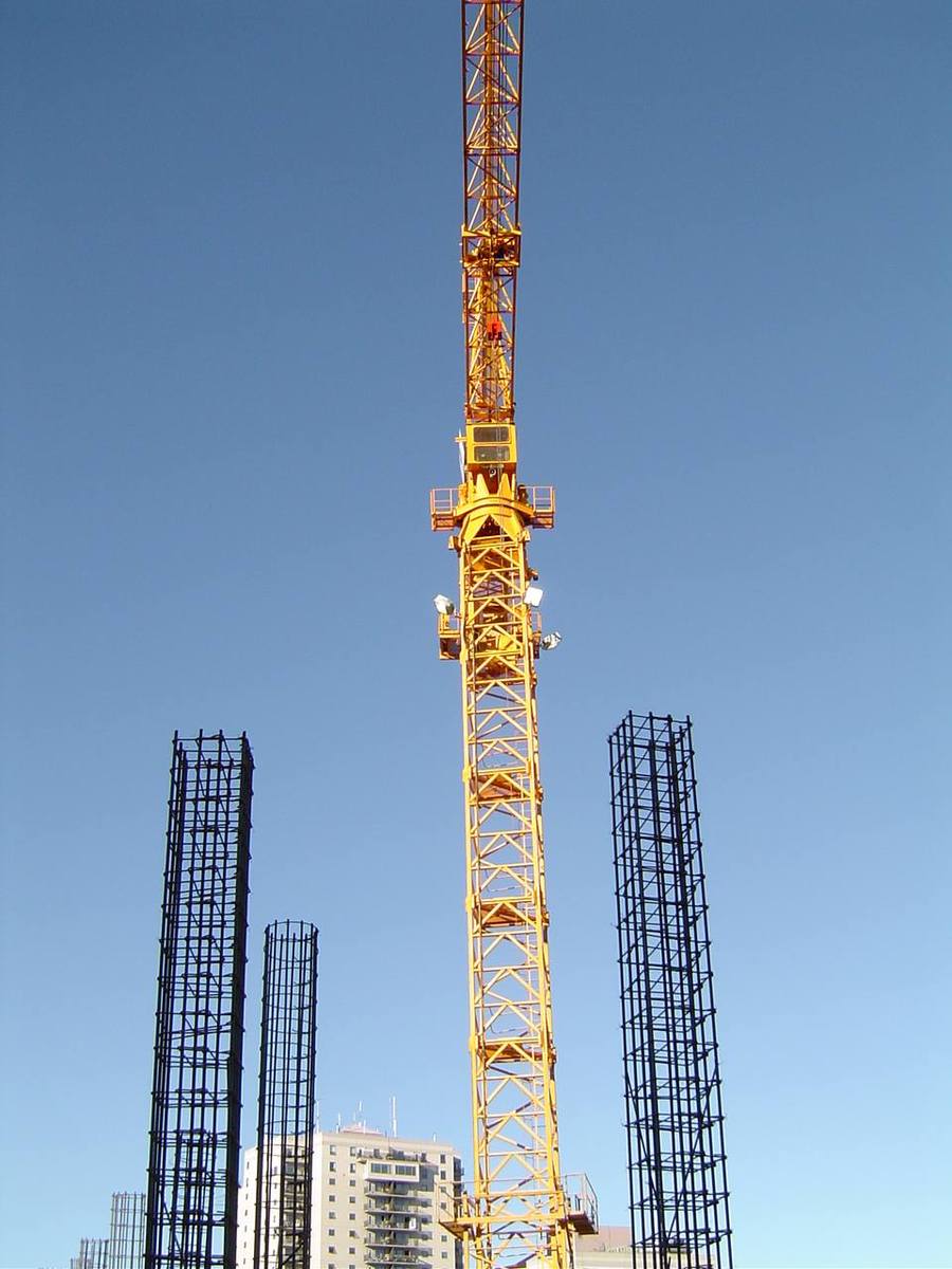a yellow tower crane sits atop a large construction area