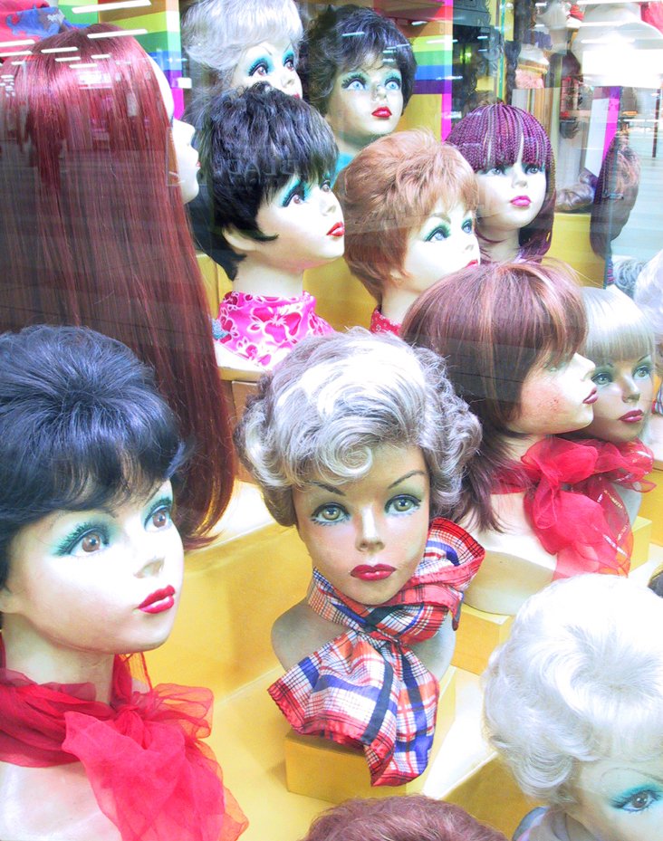 a store window displays various wigs and hair
