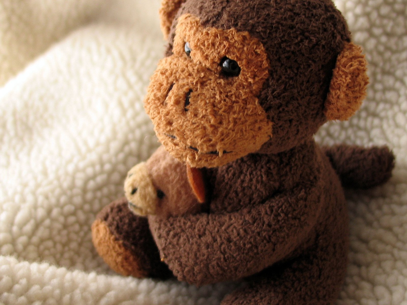 a small brown teddy bear sitting on top of a white blanket