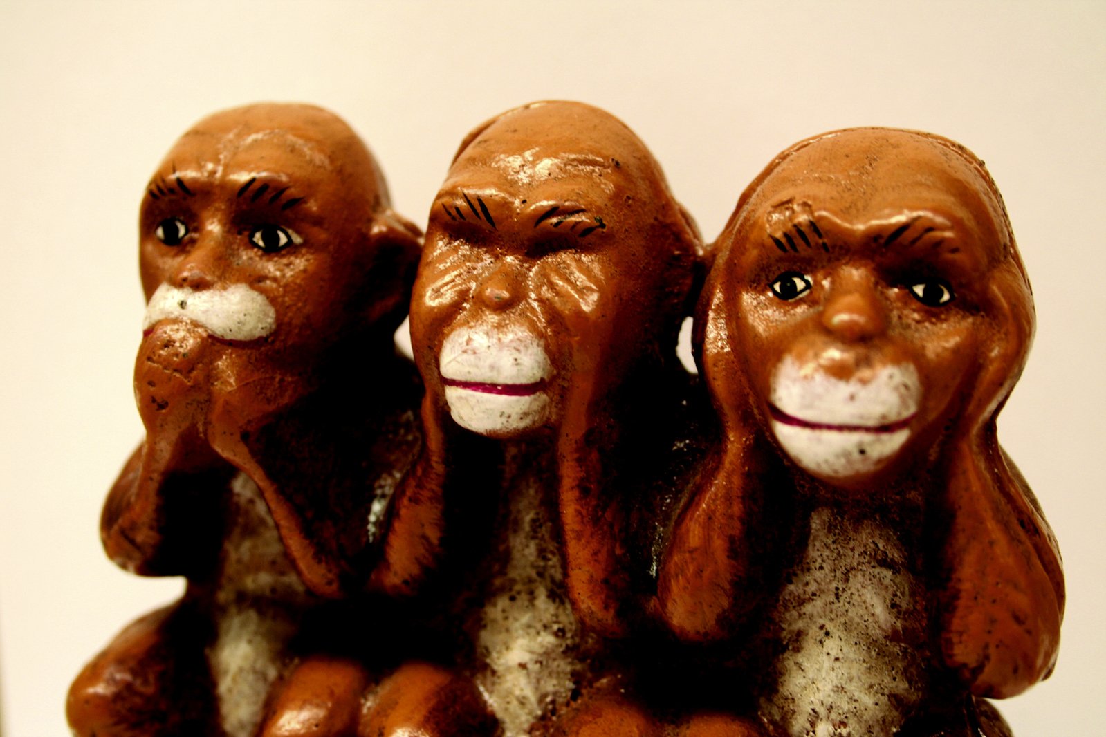 three chocolate monkey sculptures sit together against a white wall