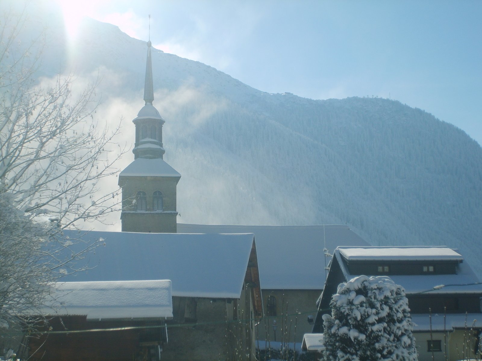 a snowy mountain scene with a church steeple in the background