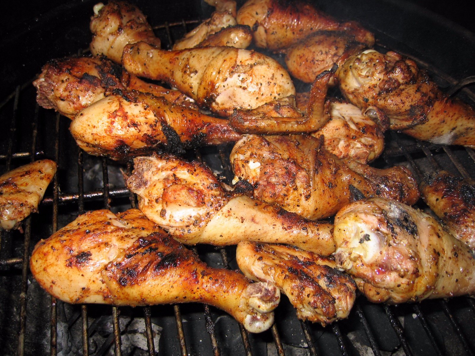 several chicken drums roasting on a charcoal grill