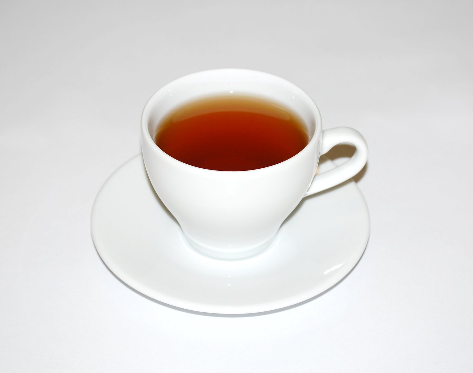 a white teacup with tea is sitting on a saucer