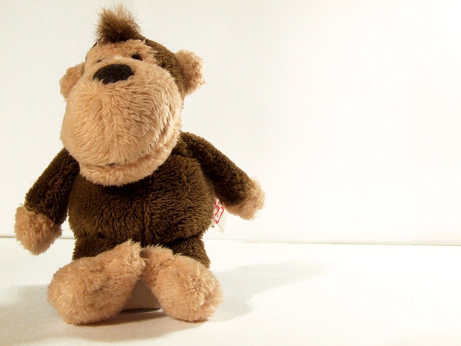 a plush monkey sitting down with his back turned