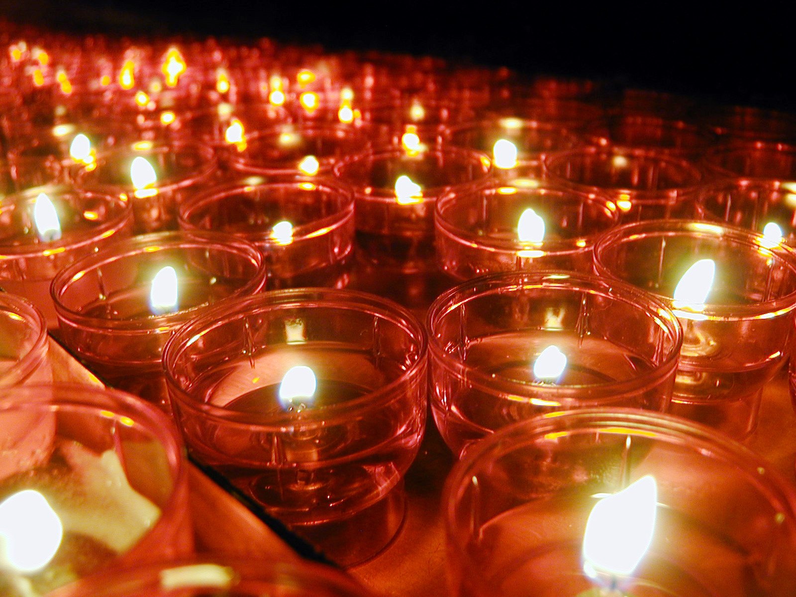 a group of votive candles lit inside a container