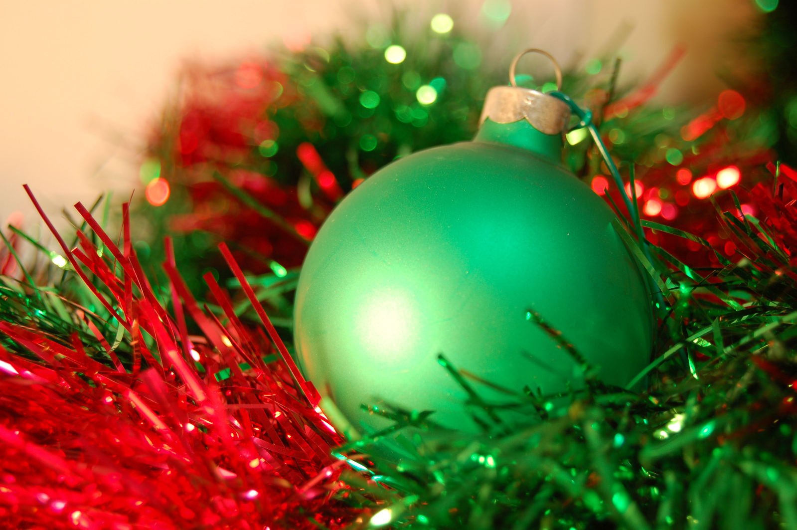 a green ornament with a red tinsel on it