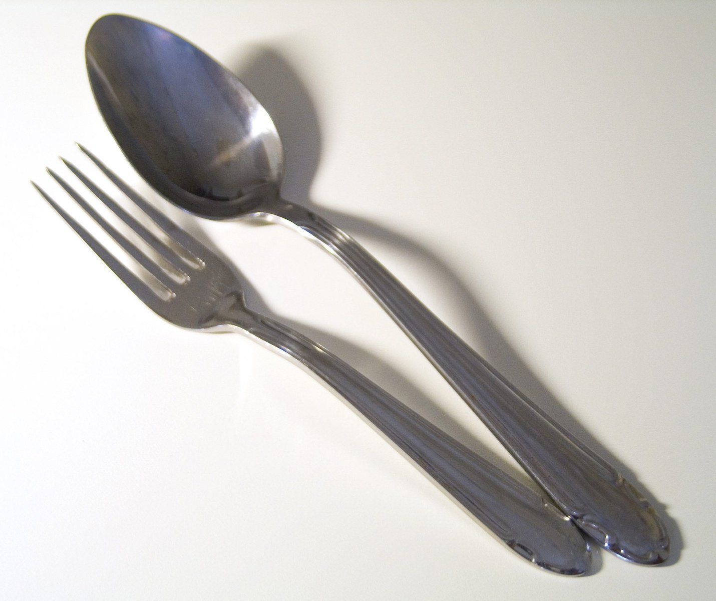 two forks and spoons on a white surface